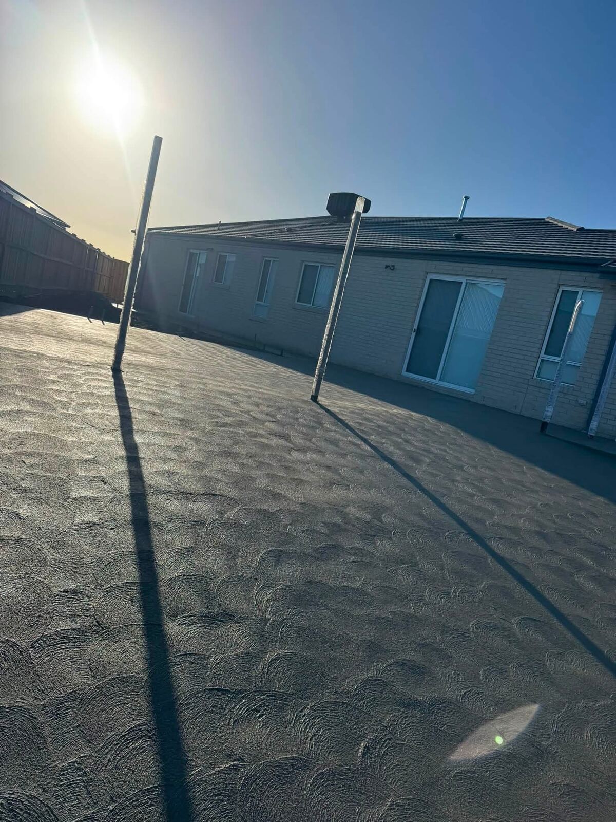 Textured broom-finish concrete courtyard behind a house