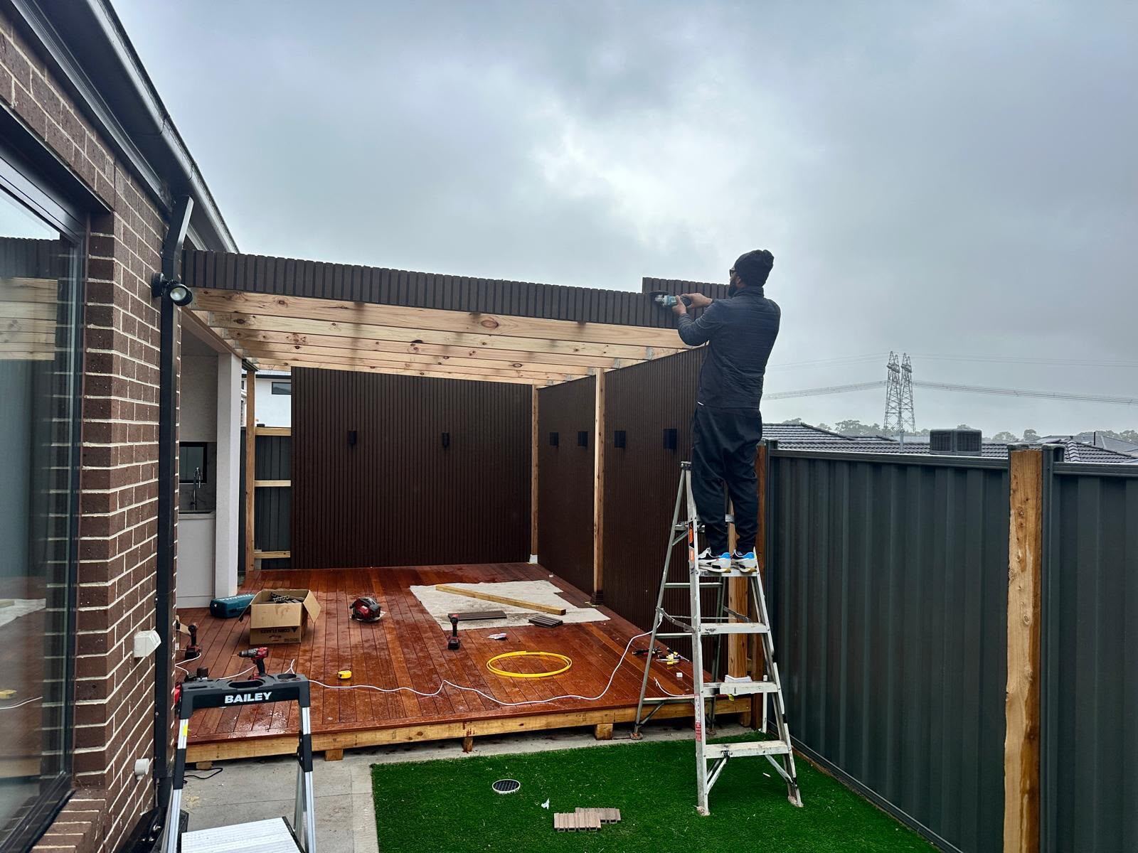 Pergola frame and roof being built over a new hardwood deck