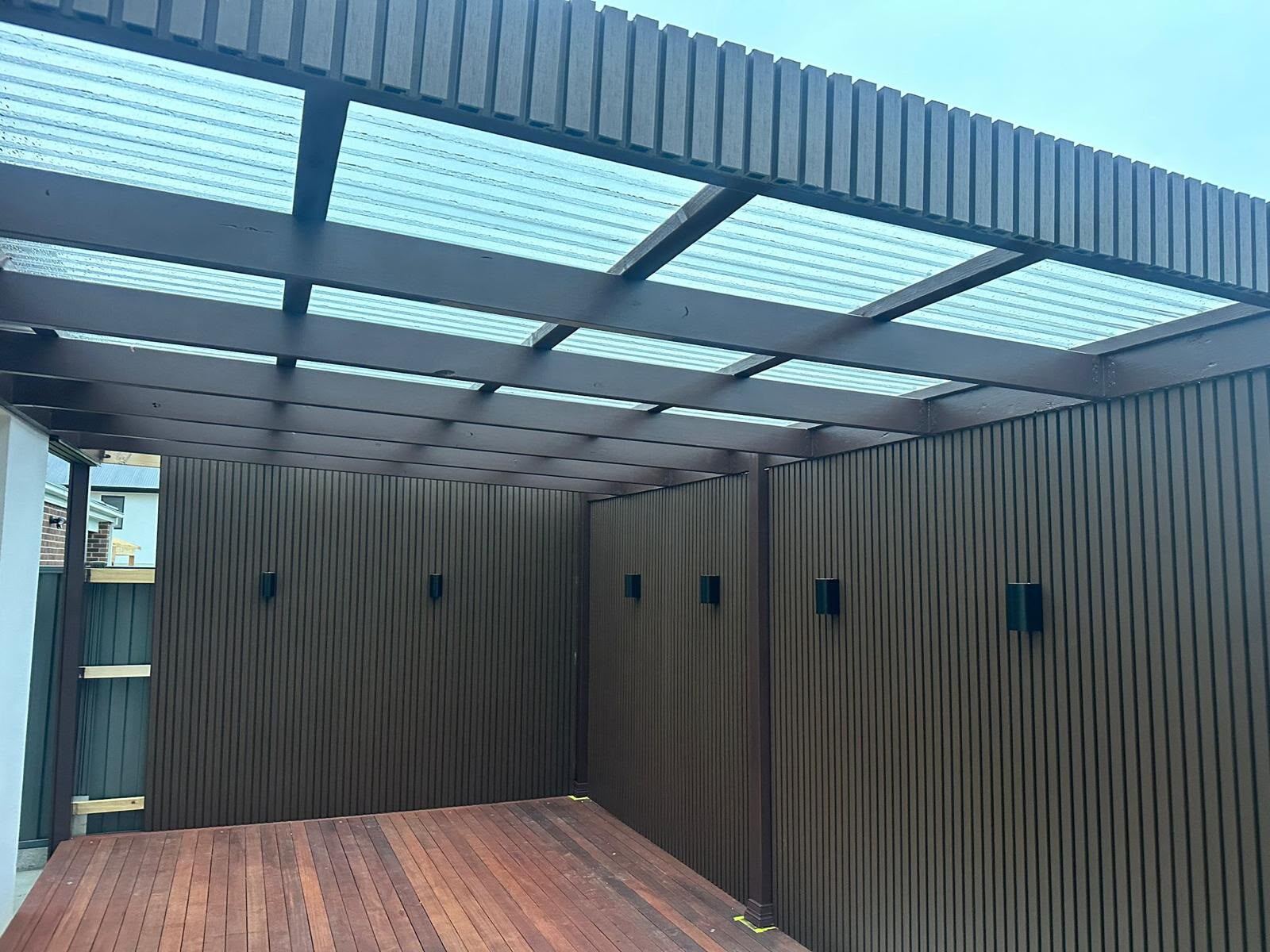 Completed pergola with polycarbonate roof and slatted cladding wall